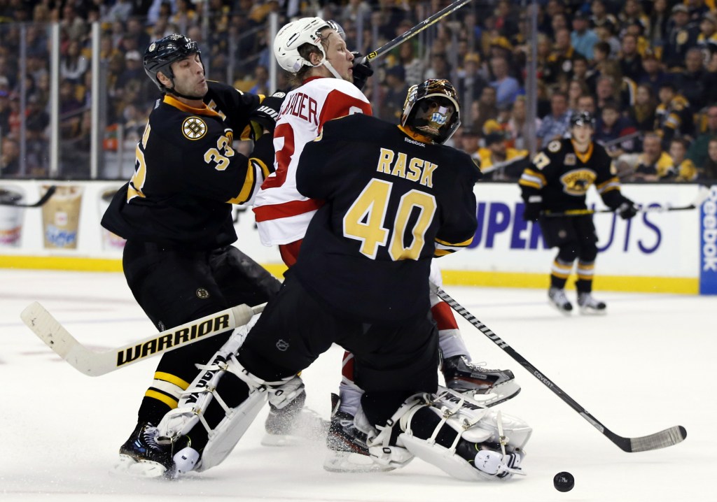 Detroit Red Wings left wing Justin Abdelkader (8) is checked by Boston Bruins defenseman Zdeno Chara (33) and goalie Tuukka Rask (40) in front of the crease in the third period of an NHL hockey game in Boston, Monday, Oct. 14, 2013. The Red Wings won 3-2.
