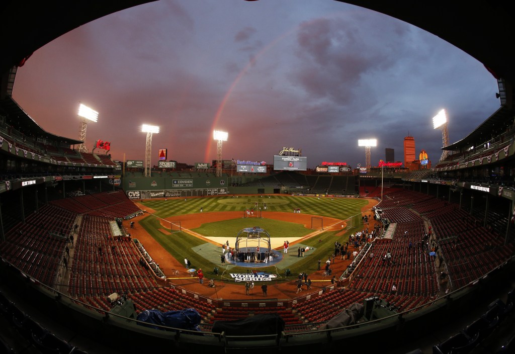 In this image taken with a fisheye lens, Boston Red Sox players take batting practice as a rainbow appears in the sky above Fenway Park Tuesday, Oct. 22, 2013, in Boston. With the Boston Red Sox back in the World Series, Wednesday’s television ratings jumped for the opener.