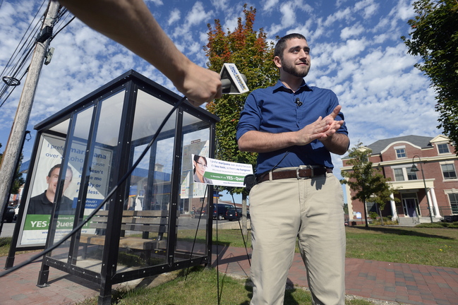 David Boyer of the Marijuana Policy Project speaks with the press near a bus shelter on Park Street in Portland that displays one of the ads in support of an initiative to remove penalties for marijuana possession.