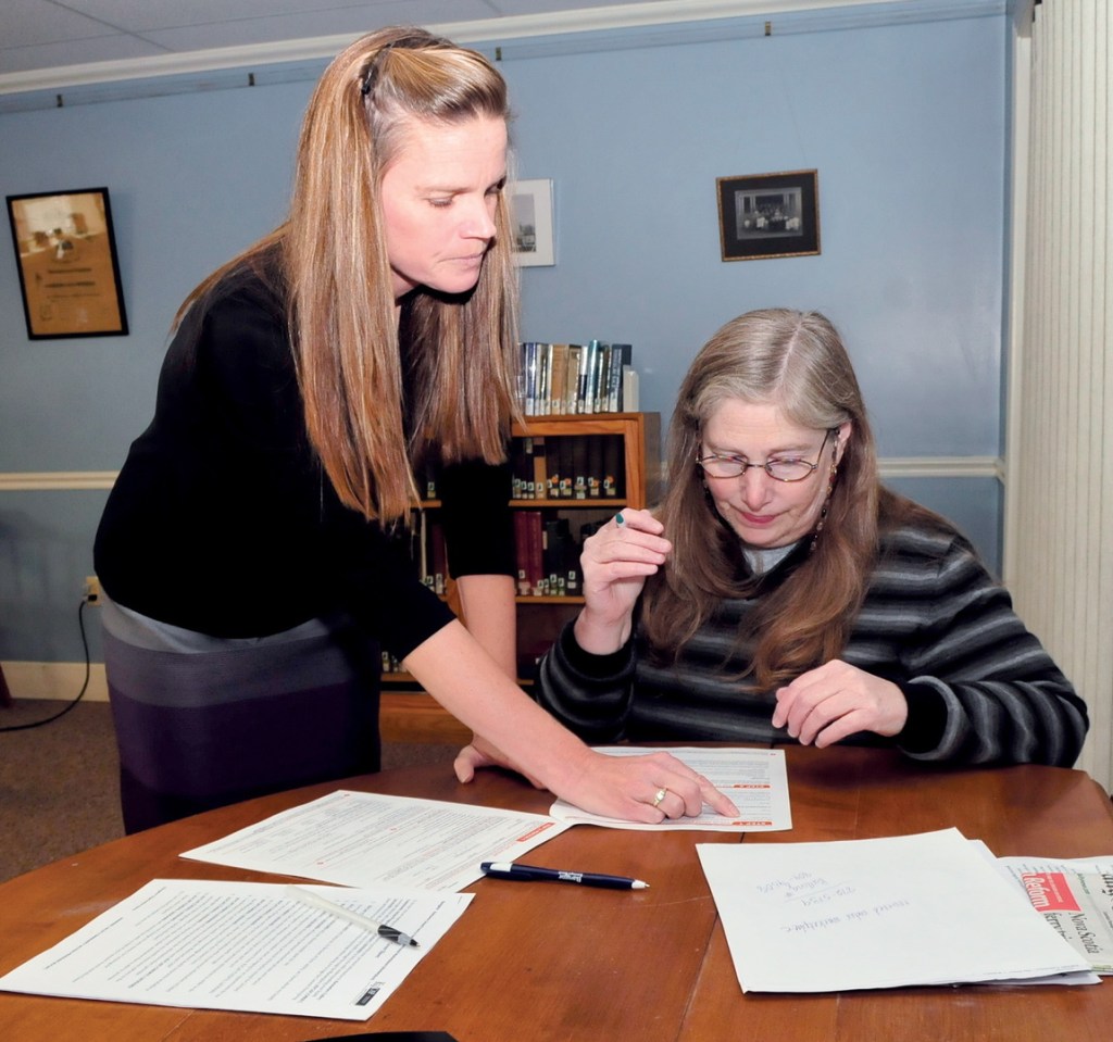 Health navigator Cheryl Leonard, left, assists Amy Goldstein with Affordable Health Care paperwork after attempts to work on the program website failed at the Winslow Public Library on Monday.