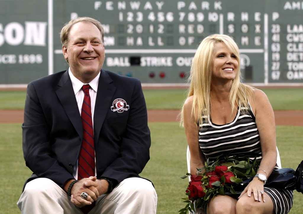 In this Aug. 3, 2012 file photo, former Boston Red Sox pitcher Curt Schilling sits with his wife Shonda, right, after being introduced as a new member of the Red Sox Hall of Fame before a baseball game between the Red Sox and the Minnesota Twins at Fenway Park in Boston. Schilling, whose video game company collapsed into bankruptcy, is selling off furniture, sports collectibles and even artificial plants from his Massachusetts home. An estate sale company has scheduled a sale of items from Schilling’s seven-bedroom, 8,000-square-foot Medfield residence for Saturday, Oct. 12, 2013.