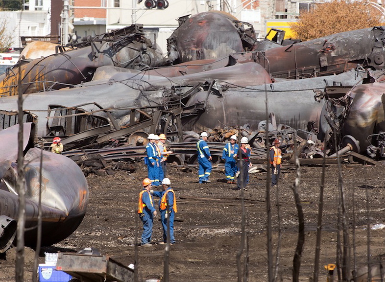 Workers stand before mangled tanker cars Tuesday, July 16 at the crash site of the train derailment and fire in Lac-Megantic, Quebec. The July 6 accident left 47 people dead.