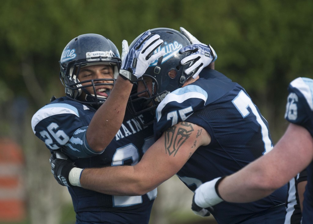 Maine running back Nigel Jones (26) and teammate Joseph Hook (75) celebrate in the first half of an NCAA college football game against Delaware in Orono, Maine, Saturday, Oct. 5, 2013.