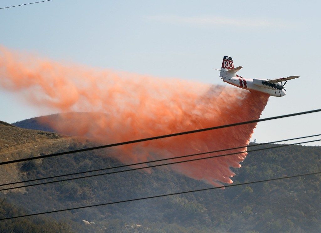A California Department of Forestry firefighting aircraft preventatively drops retardant on a ridge above Baker Canyon in Orange County, Calif. Sunday, Oct. 6, 2013. The mulch pile fire reported late Sunday morning quickly spread to surrounding wild vegetation, said Orange County Fire Authority Capt. Steve Concialdi. No homes were threatened.