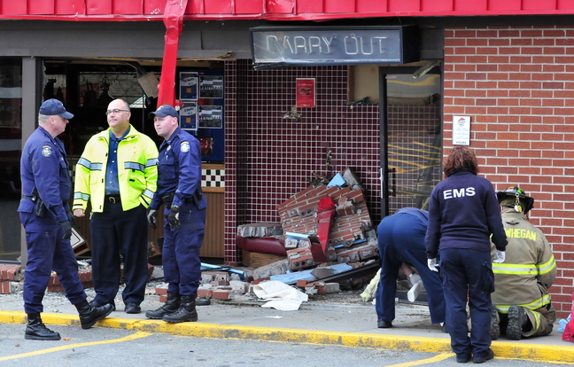 AFTERMATH: Firefighters, state police and Skowhegan Police Chief Ted Blais, second from left, investigate the scene where a truck loaded with wood crashed into the Pizza Hut restaurant in Skowhegan on Monday.