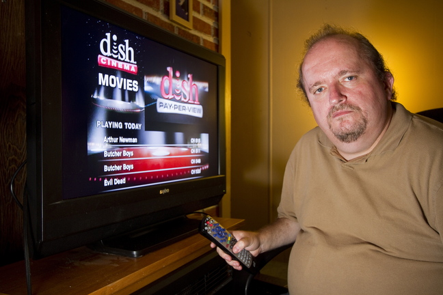Tim Ryan of Lisbon sits in front of his television with Dish Network service last month. Ryan canceled his Time Warner TV service in favor of the DISH network after eight years as a Time Warner customer. He said price increases and rigid customer service representatives – who shut his service off after he missed his bill deadline by a day – convinced him to drop the cable provider.