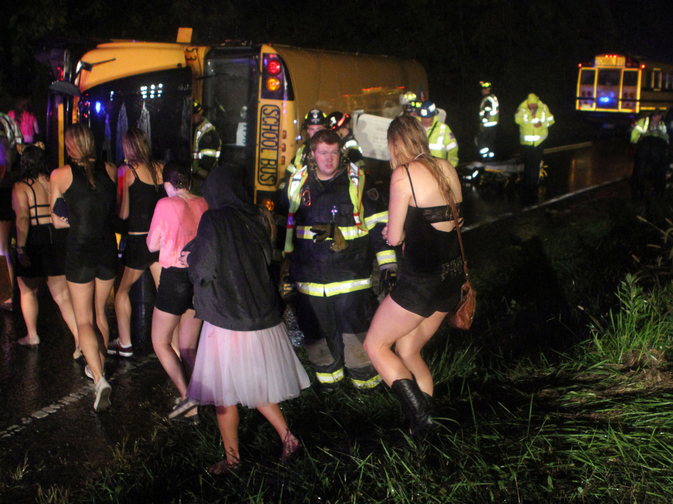 Passengers walk past the bus that overturned after colliding with a car carrier truck in Bear, Del., Thursday evening.