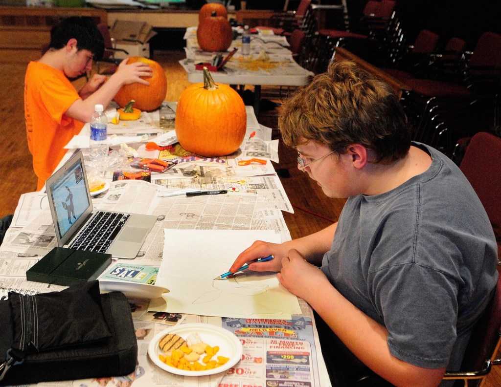 Pumpkin Carving: Corey Boynton, top left, carves a pumpkin while Everett Hotham draws during the After School Art Program on Wednesday at Johnson Hall in Gardiner.