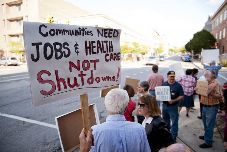 Demonstrators hold signs while protesting outside the Lafayatte, Ind. office of U.S. Representative Todd Rokita, Thursday, Oct. 3, 2013. They were protesting the government shutdown and Rokita’s stance on it.