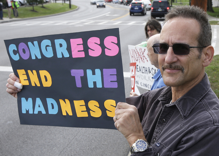 Steven Ahrenholz, a furloughed federal worker, protests outside the Department of Health and Human Services CDC offices Tuesday in Cincinnati. The government shutdown is entering its third week. House GOP leaders Tuesday floated a plan to fellow Republicans to counter an emerging Senate deal to reopen the government and forestall an economy-rattling default on U.S. obligations. But the plan got mixed reviews from the rank and file and it was not clear whether it could pass the chamber.