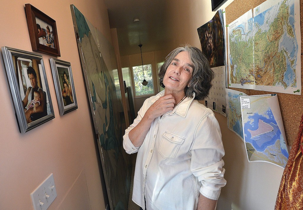 Maggy Willcox, wife of Peter Willcox, captain of the Greenpeace vessel Arctic Sunrise, stands near photos of her husband with his children on a wall in his boyhood home, in Norwalk, Conn. Willcox spoke with her husband Monday for the first time since he was arrested in September during a protest in the Arctic.