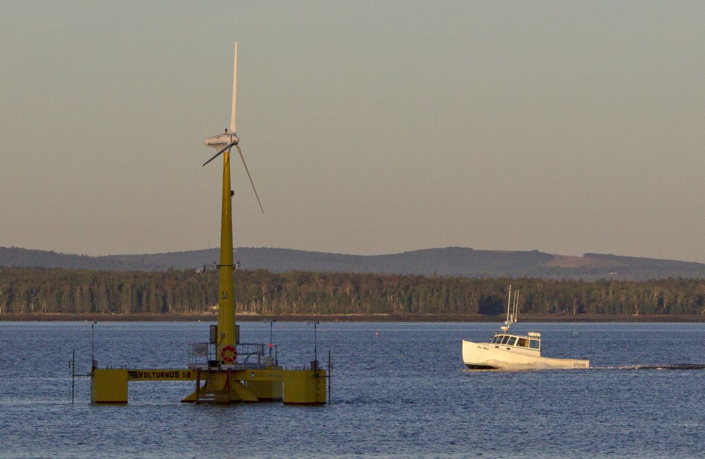 A lobster boat passes a floating wind turbine off the coast of Castine in September. The University of Maine’s 9,000-pound prototype has been generating power since the summer.