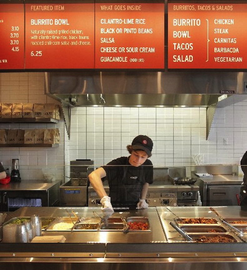 In this December 2010 file photo, Kyle Braley stirs a tomatillo green chili salsa at Chipotle Mexican Grill in South Portland. The popular restaurant chain, which serves naturally-raised beef, chicken and pork, has seen its profits skyrocket as more Americans look for slightly higher-quality fast food.
