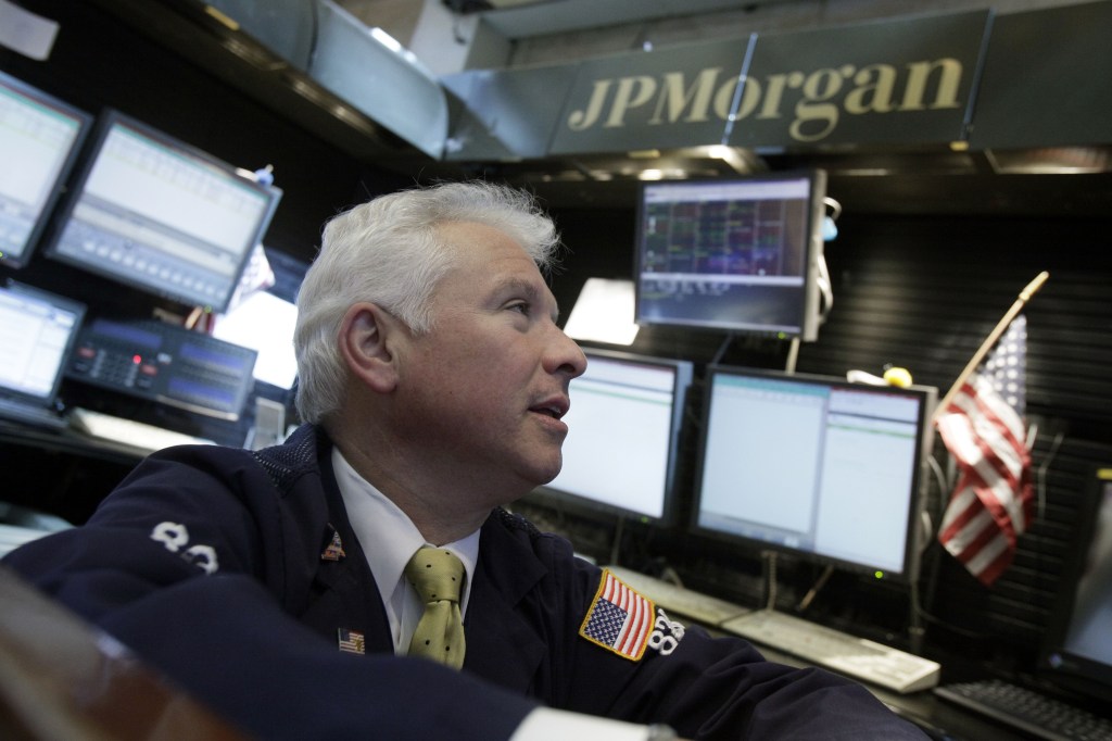 Peter Castelli, a vice president with JP Morgan, works in his firm’s booth on the floor of the New York Stock Exchange.