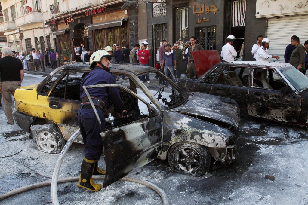 Firefighters extinguish a burning vehicle after two mortar rounds struck the Abu Roumaneh area in Damascus, Syria, on Saturda. Syria’s state news agency said two mortar rounds struck an upscale neighborhood in the Syrian capital of Damascus, killing at least one child and injuring a dozen people.