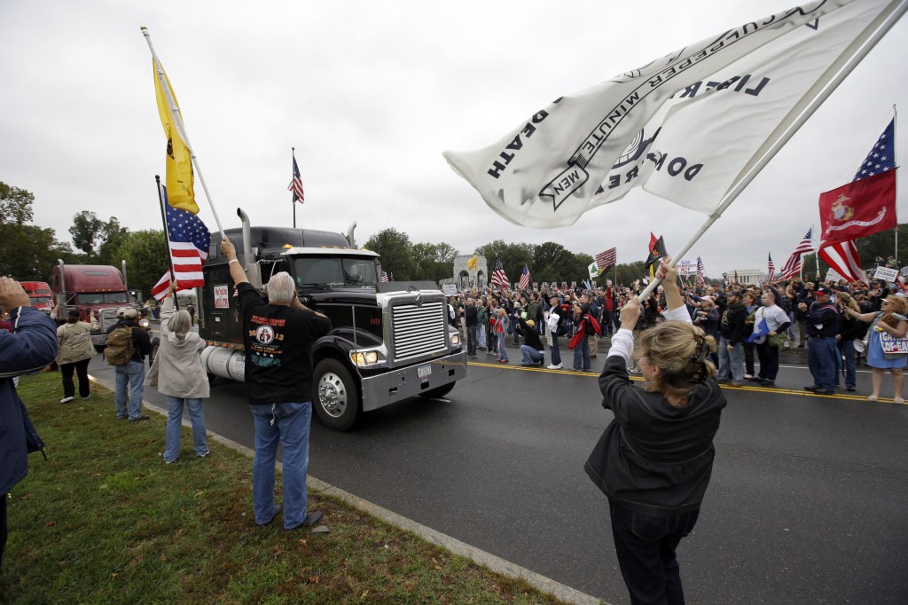 Protesters cheer as large trucks arrive at a rally at the World War II Memorial on the National Mall in Washington Sunday, Oct. 13, 2013. Leaders in the U.S. Senate have taken the helm in the search for a deal to end the partial government shutdown and avert a federal default. The rally was organized to protest the closure of the Memorial, subsequent to the shutdown, and lack of access to it by World War II veterans, who traveled there on Honor Flight visits.