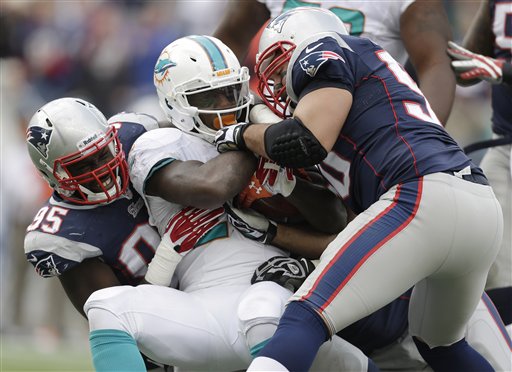 New England Patriots defensive ends Chandler Jones and Rob Ninkovich tackle Miami Dolphins running back Lamar Miller in the third quarter of the Patriots' 27-17 win Sunday at Gillette Stadium in Foxborough, Mass.