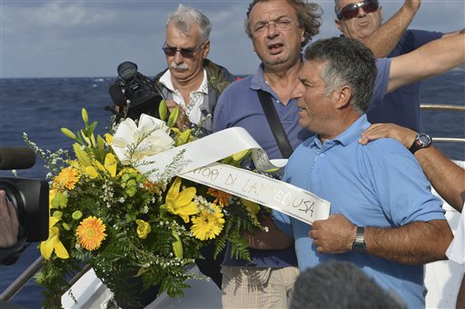 Fishing boat captain Calosero Spalma, right, today throws a wreath, with writing on a ribbon written in Italian, "Fishermen of Lampedusa," into the sea to pay tribute to the victims of Thursday's migrant shipwreck off the coast of the southern Italian island of Lampedusa. A 20-meter boat packed with migrants sank Thursday when the ship capsized after they started a fire to attract attention. Just 155 people survived, 111 bodies have been recovered and more than 200 are still missing.