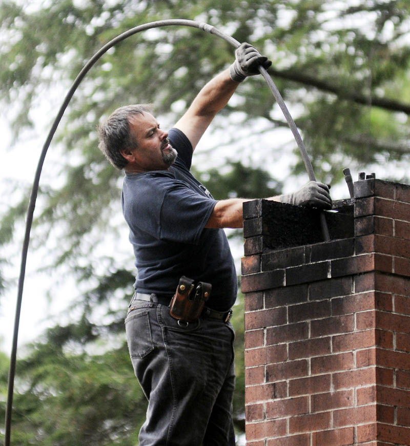 SWEEP: Dave Pelletier of Downeast Chimney sweeps a flume on a home in Litchfield on Wednesday October 23, 2013.