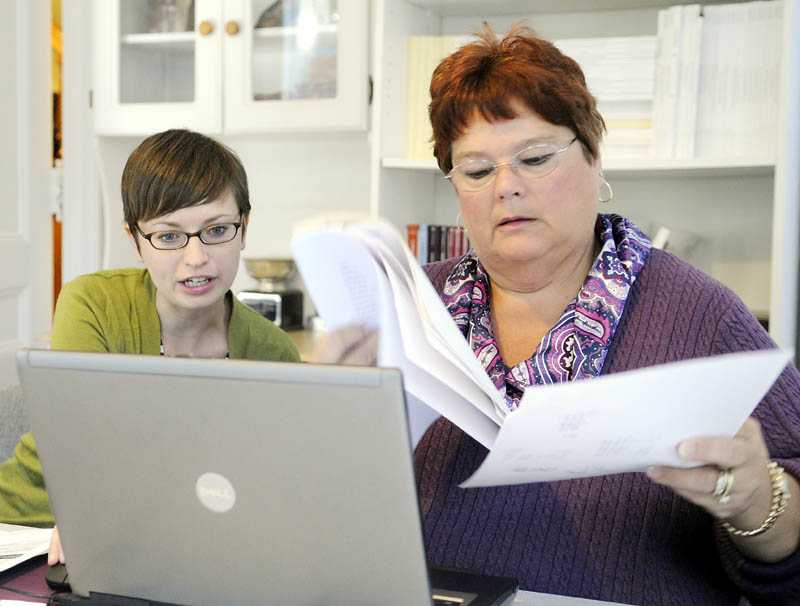 Emily Brostek, left, assists Charlene Brousseau with enrolling in an Affordable Care Act insurance exchange today at Brostek's office in Augusta. Online enrollments have encountered delays, but people wishing to to enroll can telephone or fill out paper forms.