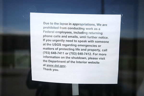 A paper sign describing the government shutdown hangs on the entrance of the U.S. Geological Service building on Whitten Road in Hallowell.