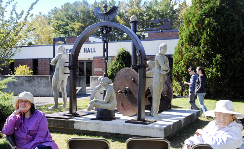 People gather around a sculpture Tuesday outside of Jewett Hall at the University of Maine in Augusta following a dedication ceremony for the piece titled "Imperfection is the Greatness of Man." Students devoted five months to creating the sculpture, which was relocated from the Viles Arboretum to its new permanent location on the campus green.