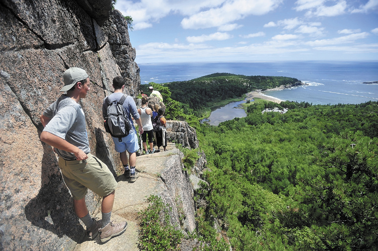 A line of hikers files up the Beehive Trail near Sand Beach at Acadia National Park in Bar Harbor in July. The park may need to close at the height of the fall foliage season if congress can't reach a deal on federal spending.