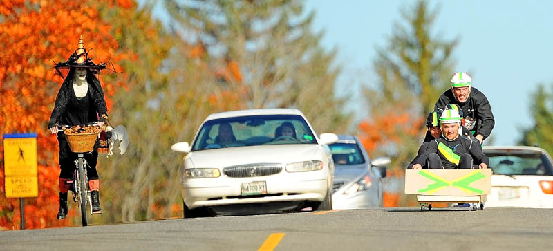 Men dressed as the Jamaican bobsled team ride their bobsled down Mayflower Hill Drive at Colby College during the Freaky 5K Fun Run organized by Hardy Girls Healthy Women today. Laura Patterson, far left, rides her bike dressed as a witch.