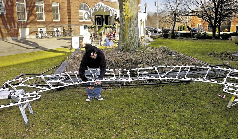 Matt Hankey, a volunteer with Waterville Main Street, works on the Kringleville sign at Castconguay Square in Waterville.