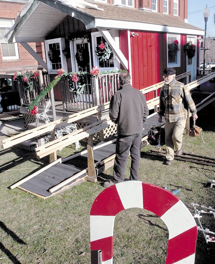 Chuck Lakin carries his tools toward Steve Buzzell after Lakin finished installing the wheelchair ramp beside Kringleville in Castonquay Square in Waterville in a previous year.