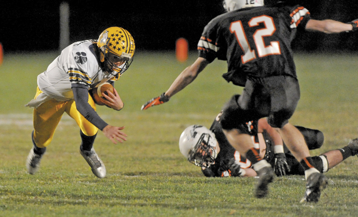 Mt. Blue quarterback Andrew Pratt gets tripped up by Skowhegan's Gus Benson, 52, in the first quarter of the Cougars' 42-40 win Friday night in Skowhegan.