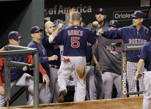 Boston Red Sox Jonny Gomes is greeted by teammates in the dugout after scoring on a single by David Ross in the fourth inning of a baseball game against the Baltimore Orioles, Saturday, Sept. 28, 2013, in Baltimore. (AP Photo/Patrick Semansky)