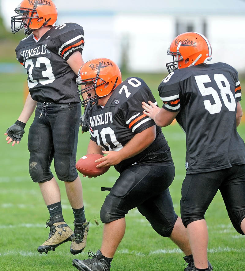 COMING UP BIG: Winslow High School’s Aaron Lint, center, celebrates after recovering a fumble earlier this season. Lint is part of a Black Raiders defensive line that has helped Winslow hold its opponents to just 12 points per game this season.
