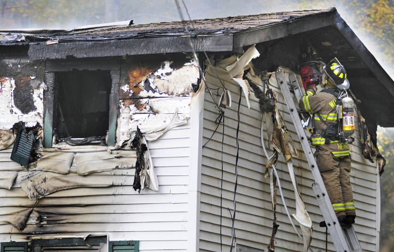 Firefighters cut a ventilation hole while crews work at 119 Granite Hill Road today in Manchester.