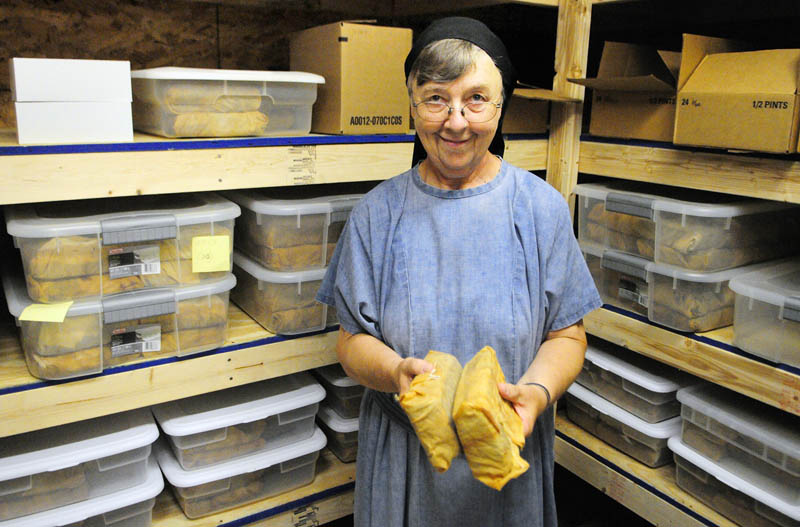 Sister Elizabeth Wagner holds two English Style fruit cakes wrapped in brandy-soaked clothes on Thursday at Transfiguration Hermitage in Windsor. Sister Bernadette Kasinathan bakes the cakes earlier in the year and they're aged in sealed plastic tubs till Wagner decorates and mails them out as orders come in the fall.