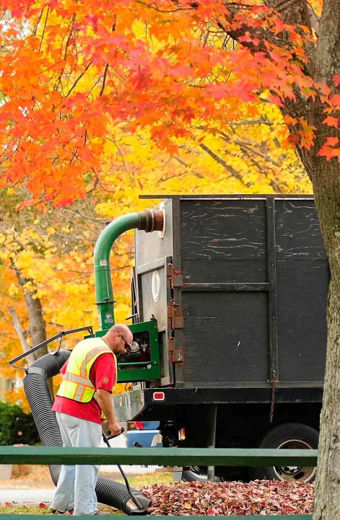 Daniel Robideau vacuums up leaves on Tuesday around the perimeter of the Gardiner Common in Gardiner. He and another city employee who was driving the truck had earlier used leaf blowers to clean off the Common and make windrows of leaves along the curb. Robideau said that they'd probably have to do it a few more times this season.