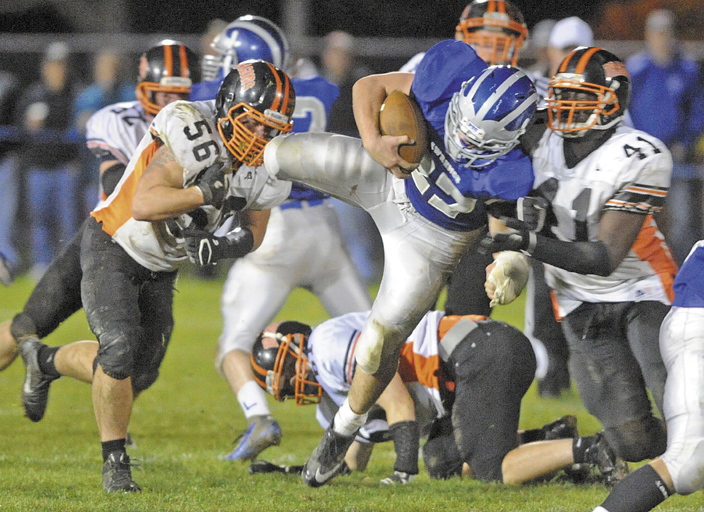 Lawrence fullback Beau Grenier, 27, gets tackled by Brunswick defenders Jacob Duffy, left, and Josh Mays, 41 in the second quarter Friday night in Fairfield.