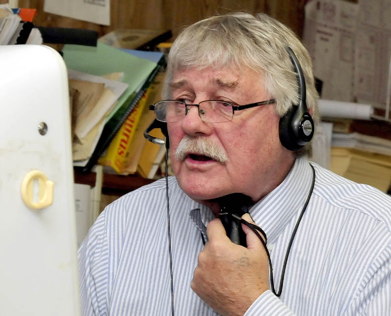 Morning Sentinel reporter Doug Harlow speaks with a subject on the phone while using an electro larynx battery-powered voicebox device.