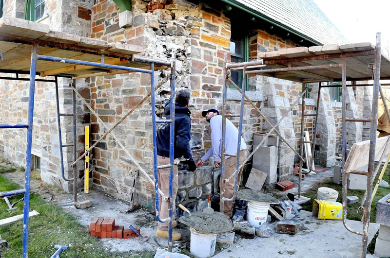 Joseph Lynch, left, and Eric Timmins repair stonework on the outside of the Pine Grove Cemetery chapel in Waterville on Monday. Timmens found a time capsule box near the corner stone of the building that contains four 1907 Morning Sentinel pages and a penny.