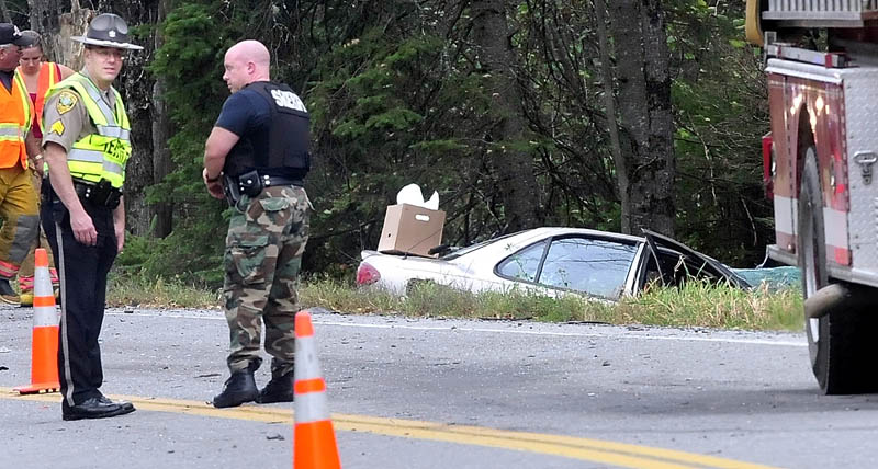 Kennebec Sheriff Office Sgt. Frank Hatch, left, surveys the scene of a two-vehicle fatal accident on Route 139 in Unity Township on Monday. A 59-year-old woman died in the Chevrolet Cavalier, background, after it collided with a pickup truck driving in the opposite direction, according to Hatch.