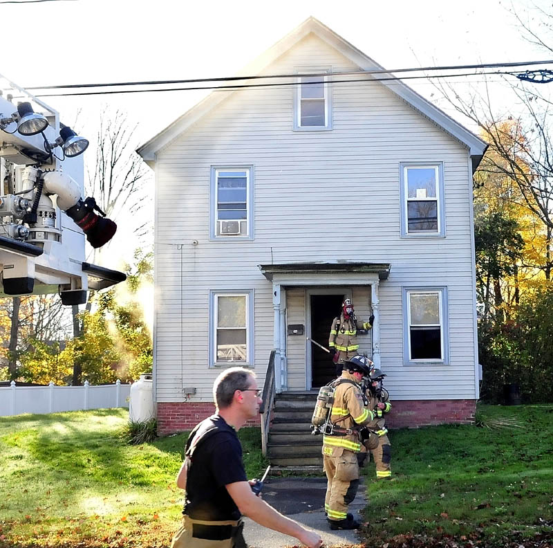 Firefighters fight a stubborn and smokey fire at a home on Oak Street in Waterville on Wednesday.