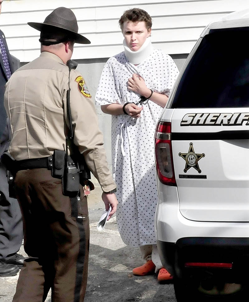 Wearing a hospital gown and neck brace from injuries sustained on Tuesday, suspect Zachary Wittke is led into a Franklin County Sheriff transport vehicle following a hearing on charges of eluding police, passing a roadblock and aggravated criminal mischief.
