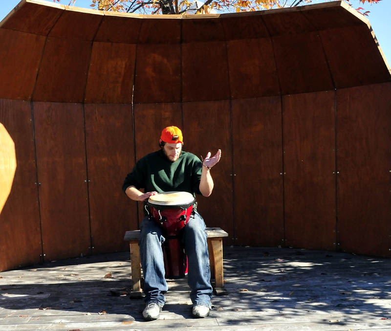 Lucas Lovejoy plays the djembe drum inside the stage at the park in the Concourse in Waterville on Tuesday. Lovejoy said the music sounded good as it bounced off nearby building walls. "It's real cool," Lovejoy said.