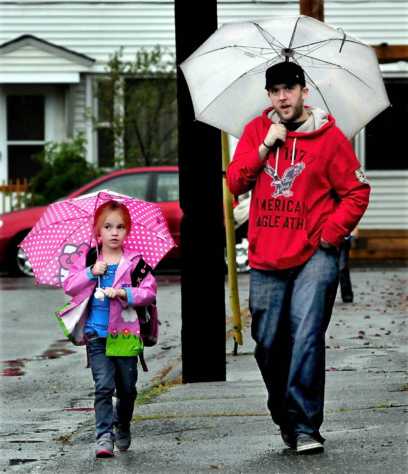 Arthur Caron walks Roslyn Leary home in the rain in Waterville on Monday. The rest of the week is expected to be sunny with moderate temperatures.