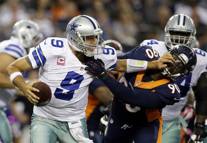 Dallas quarterback Tony Romo, who threw for 506 yards, attempts to fight off a sack by Denver’s Shaun Phillips late in the fourth quarter of a high-scoring affair in Arlington, Texas. The Broncos won 51-48.