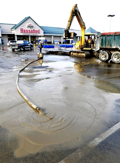 WATER PIPE BREAK: Gerald MacKenzie company workers John Cote, left, and Bob Nickerson work on repairing a water main break in the middle of the Elm Plaza shopping center parking lot in Waterville on Wednesday. Water was unavailable to stores.