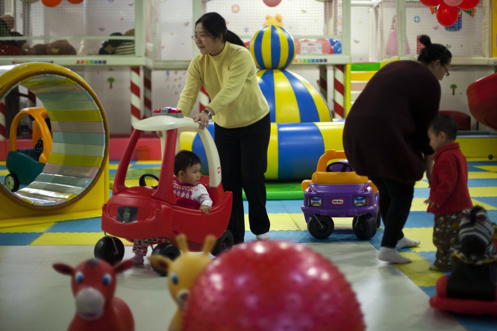Parents play with their children at a kids’ play area in a shopping mall in Beijing last January. With China’s one-child policy, birth rates plunged from 4.77 children per woman in the early 1970s to 1.64 in 2011, according to estimates by the United Nations.