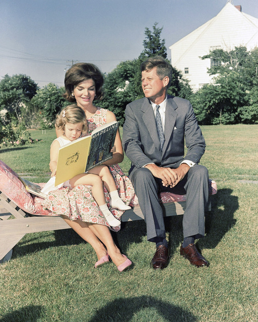 In this July 25, 1960 file photo , Sen. John F. Kennedy, D-Mass., sits with wife, Jacqueline, as she reads to their daughter, Caroline, at Hyannis Port, Mass.