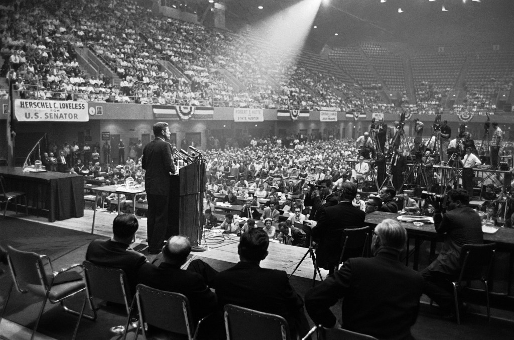 In this Aug. 21, 1960 file photo, illuminated by a spotlight, Sen. John F. Kennedy, Democratic presidential nominee, speaks to an audience in Des Moines, Iowa.