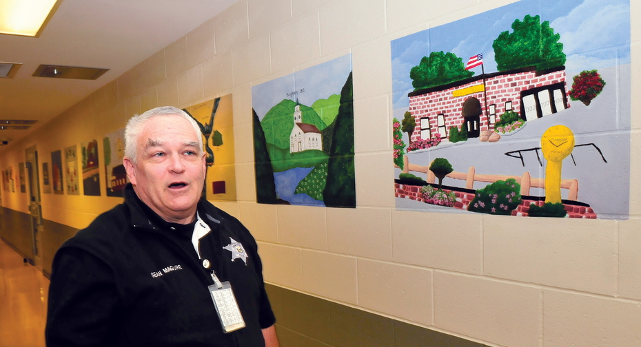 ARTFUL: Somerset County Jail officer Sean Maguire explains how 28 Somerset area town landmark paintings will be made into postcards as part of a prison industry project at the Madison facility.